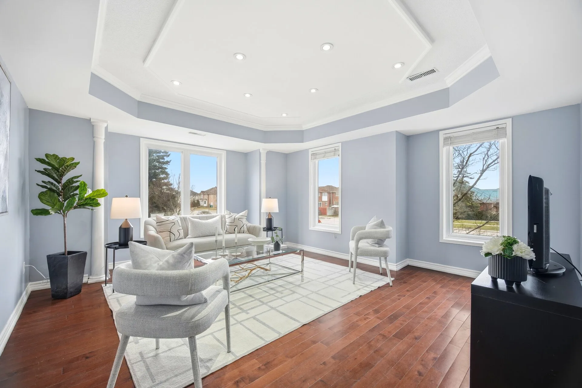 Professionally staged living room with light sofa, glass coffee table, lamps and fiddle-leaf fig