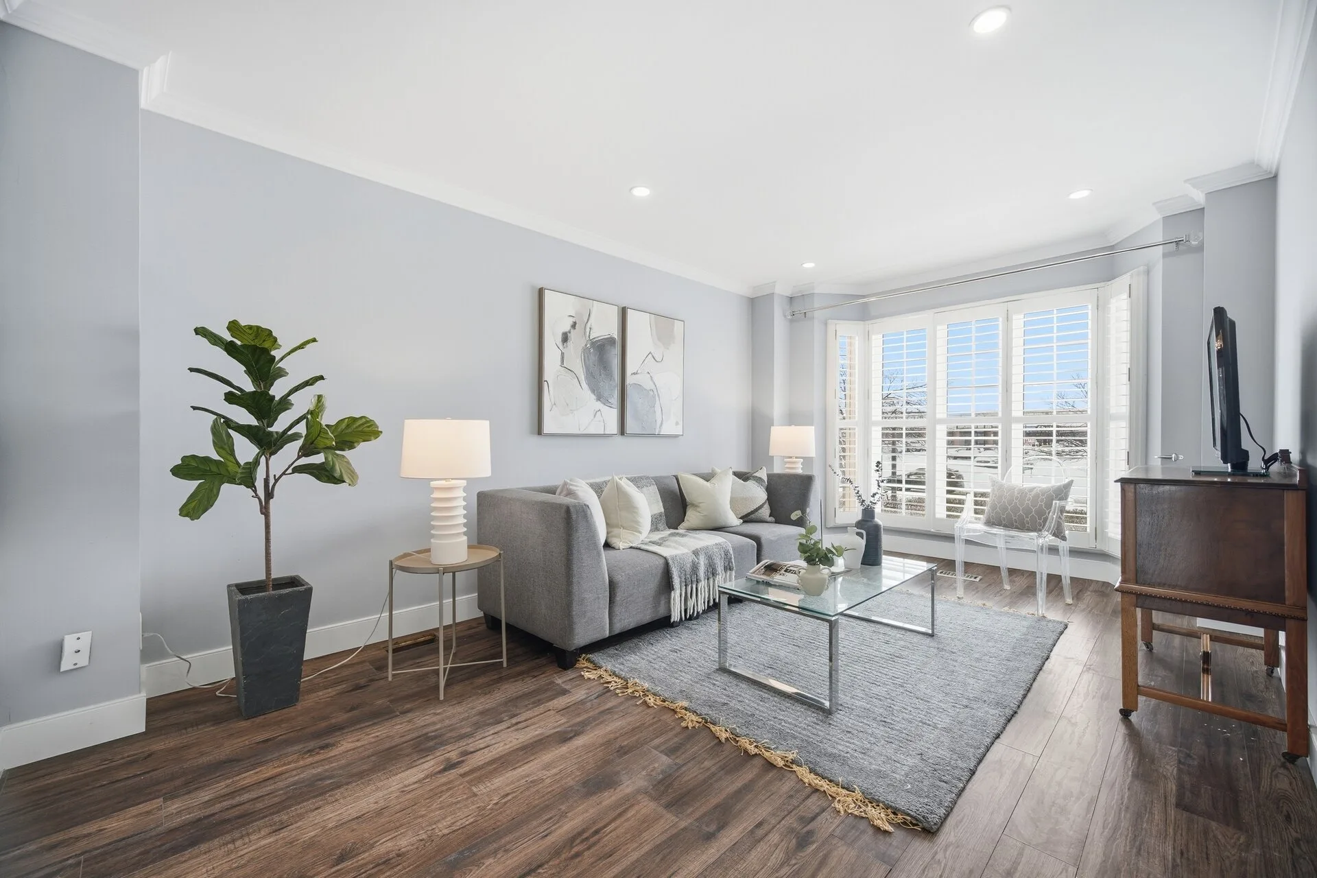 Professionally staged living room with grey sofa, wall art, rug and bay window
